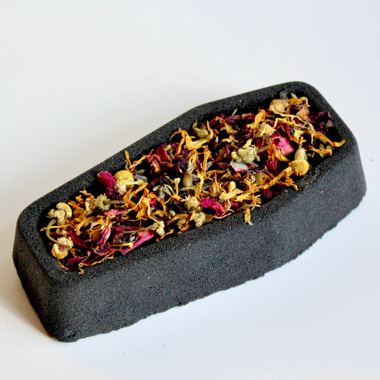 Black coffin shaped bath bomb filled with dried botanicals.